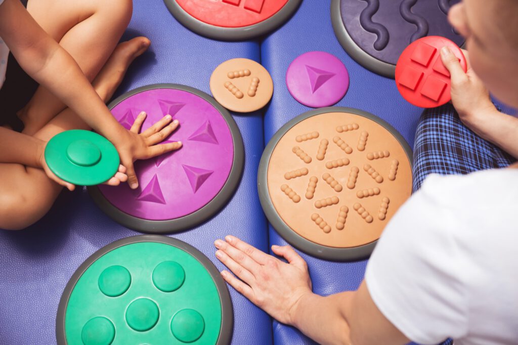 Hands-on sensory integration therapy using textured tactile pads for developmental learning support.